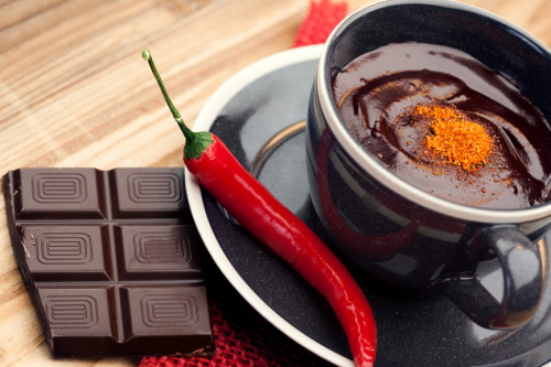 Cup of hot chocolate with chili pepper on old wooden table