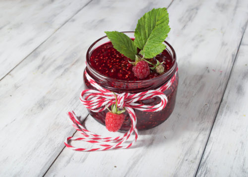 Raspberry jam in a jar on the wooden table