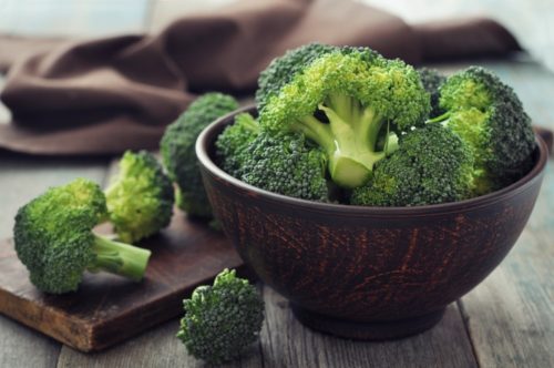 Kup sveže zelenega brokolija v rjavi posodi nad lesenim ozadjem